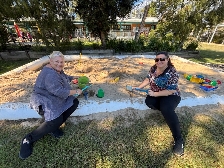 Two staff members playing in the sandpit