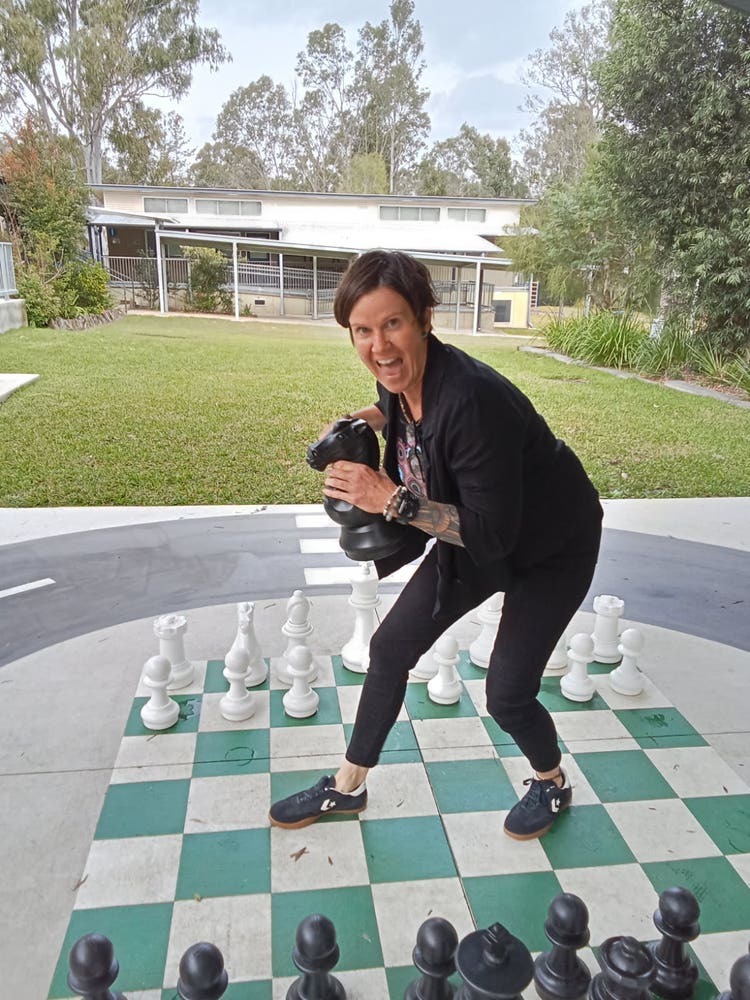 A school teacher playing outdoor chess in the playground